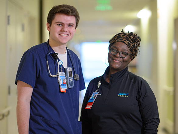 A male and a female nurse standing in a clinic's hallway talking