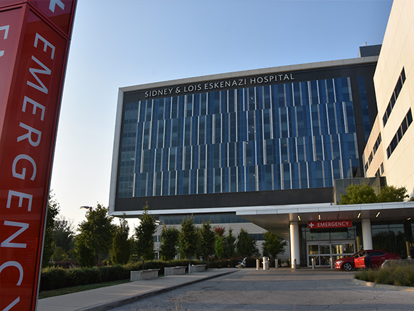 View of hospital façade from the parking lot showing emergency entrance