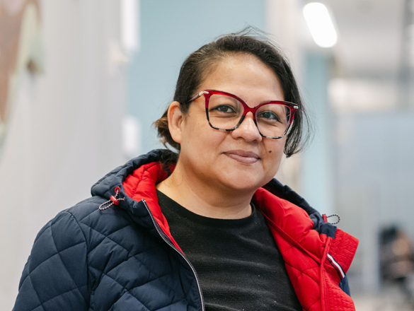 A woman with glasses, wearing a coat looks at the camera
