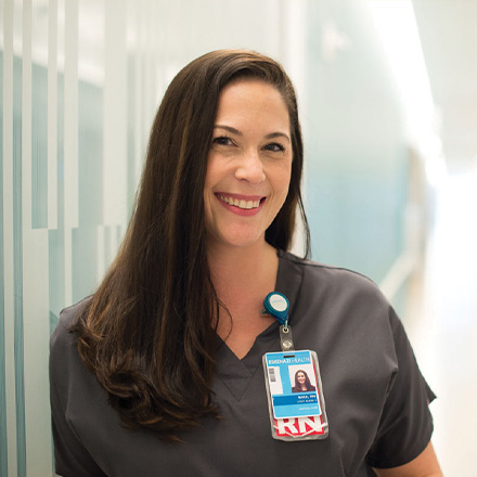 Female nurse leaning against the wall smiling at the camera